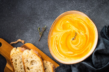 Wall Mural - Pumpkin soup with cream at black stone table. Healthy eating. Top view with copy space.