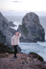 Wall Mural - A woman stands on the rocks of the coast near Cabo da Roca, Portugal.