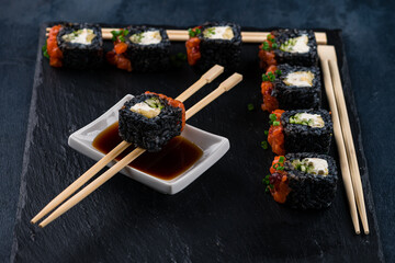 Wall Mural - Japanese black sushi rolls with salmon, cucumber, cream cheese and soy sauce.