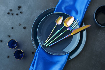 Wall Mural - Various blue china plates with blue tablecloth, gold-rimmed blue glasses, blueberries, and iridescent cutlery