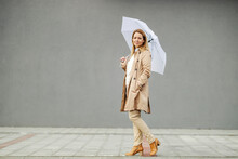 A Trendy Woman Is Posing With Umbrella On A Rainy Weather.