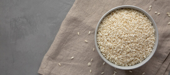 Raw Organic Carnaroli Rice in a Bowl on a gray surface, top view. Overhead, from above, flat lay. Copy space.