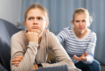 Poster - Sad female and daughter sitting at sofa and having quarrel at home