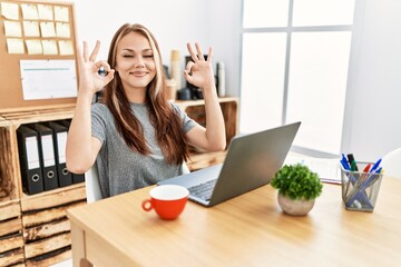 Wall Mural - Young brunette woman working at the office with laptop relax and smiling with eyes closed doing meditation gesture with fingers. yoga concept.