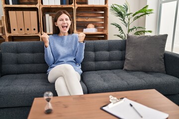 Canvas Print - Young brunette woman at consultation office celebrating surprised and amazed for success with arms raised and open eyes. winner concept.