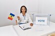 Young african american woman smiling confident holding moldova flag working at electoral college