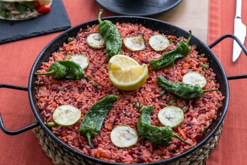 Poster - Closeup of a Spanish Paella with hot green peppers in a black pot