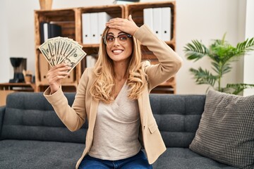 Sticker - Young blonde therapist woman working at therapy office holding money stressed and frustrated with hand on head, surprised and angry face