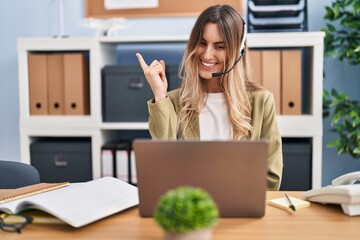 Sticker - Young hispanic woman wearing call center agent headset working at the office smiling happy pointing with hand and finger to the side