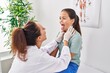 © Krakenimages.com - Woman and girl doctor and patient examining throat at clinic
