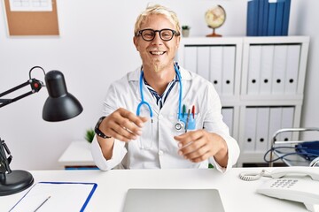 Wall Mural - Young caucasian man wearing doctor uniform talking at clinic