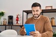 © Krakenimages.com - Young hispanic man using touchpad sitting on table at home