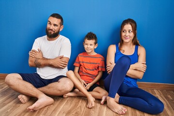 Poster - Family of three sitting on the floor at home smiling looking to the side and staring away thinking.