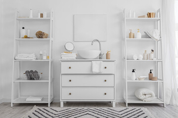 Poster - Shelf units with different bath accessories and modern sink near white wall in bathroom interior