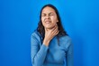 Young brazilian woman standing over blue isolated background touching painful neck, sore throat for flu, clod and infection