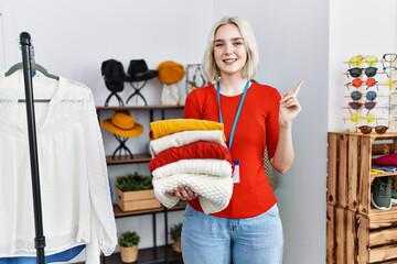 Wall Mural - Young caucasian woman working as manager at retail boutique smiling happy pointing with hand and finger to the side