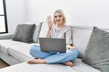 Sticker - Young caucasian woman using laptop at home sitting on the sofa showing and pointing up with fingers number five while smiling confident and happy.