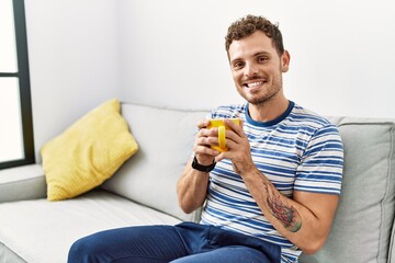 Sticker - Young hispanic man smiling confident drinking coffee at home