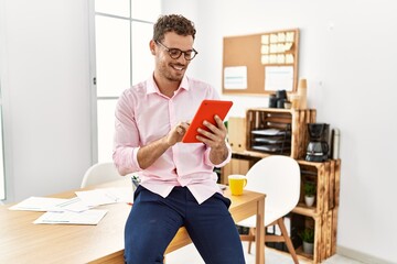 Wall Mural - Young hispanic man smiling confident using touchpad at office