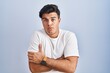 © Krakenimages.com - Hispanic man standing over blue background shaking and freezing for winter cold with sad and shock expression on face