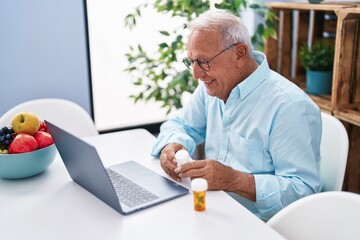 Wall Mural - Senior grey-haired man having telemedicine sitting on table at home