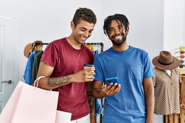 Poster - Two men friends holding shopping bags using smartphone at clothing store