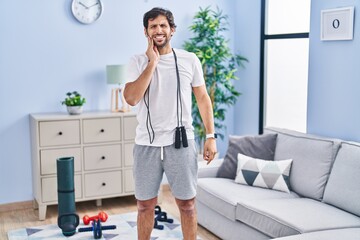 Wall Mural - Handsome latin man wearing sportswear at home touching mouth with hand with painful expression because of toothache or dental illness on teeth. dentist