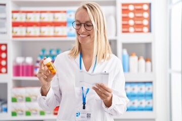 Sticker - Young blonde woman pharmacist holding pills bottle reading prescription at pharmacy