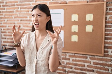 Poster - Chinese young woman working at the office doing presentation crazy and mad shouting and yelling with aggressive expression and arms raised. frustration concept.