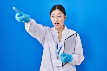 Poster - Chinese young woman working at scientist laboratory pointing with finger surprised ahead, open mouth amazed expression, something on the front