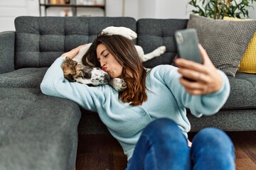 Canvas Print - Young woman kissing and hugging dog making selfie by the smartphone at home