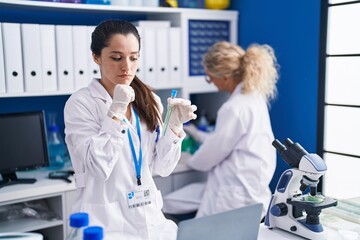 Canvas Print - Young hispanic woman working at scientist laboratory serious face thinking about question with hand on chin, thoughtful about confusing idea