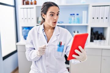 Sticker - Young brunette woman working at scientist laboratory doing online call scared and amazed with open mouth for surprise, disbelief face