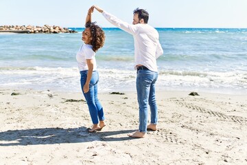 Sticker - Middle age hispanic couple smiling happy dancing at the beach.