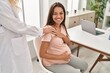 © Krakenimages.com - Young latin woman pregnant and doctor together at clinic