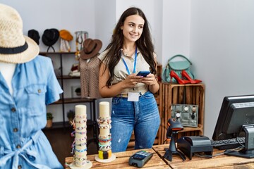 Canvas Print - Young caucasian woman using smartphone working at clothing store