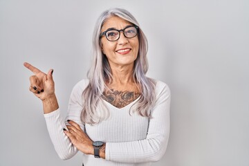 Poster - middle age woman with grey hair standing over white background with a big smile on face, pointing wi