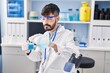 © Krakenimages.com - Young hispanic man scientist pouring liquid on glass at laboratory