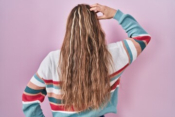 Poster - Young blonde woman standing over pink background backwards thinking about doubt with hand on head