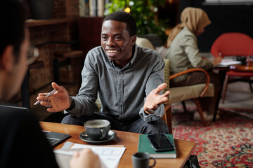 Aufkleber - Young successful African American economist explaining something or consulting colleague while sitting by table in front of him at meeting