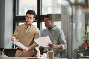 Aufkleber - Young confident multi-ethnic businessman explaining financial data in document to African American male economist during discussion