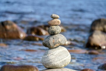 Sticker - Closeup shot of a pyramid of stones with unstable balance on the beach in daylight