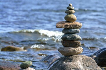 Sticker - Closeup shot of a pyramid of stones with unstable balance on the beach in daylight