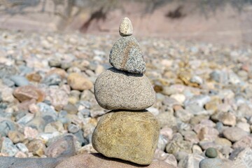 Sticker - Closeup view of a pyramid of stones with unstable balance on the beach in daylight