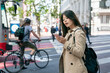 © PR Image Factory - asian chinese business woman stopping to check message on the phone as she is heading to work on the street in san Francisco California usa with a male cyclist at background