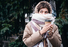 A Young Woman Wrapped In A Scarf With A Cup Of Coffee In The Winter In The Park.