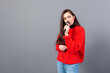 © ako-photography - young, emotional brunette with a microphone dressed in a red sweater sings karaoke or says a speech