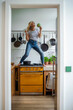 © Westend61 - Carefree woman standing on stove enjoying dancing in kitchen