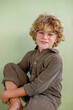 © Westend61 - Smiling boy sitting against green background