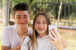 © Westend61 - Teenage girl taking selfie with boy outdoors